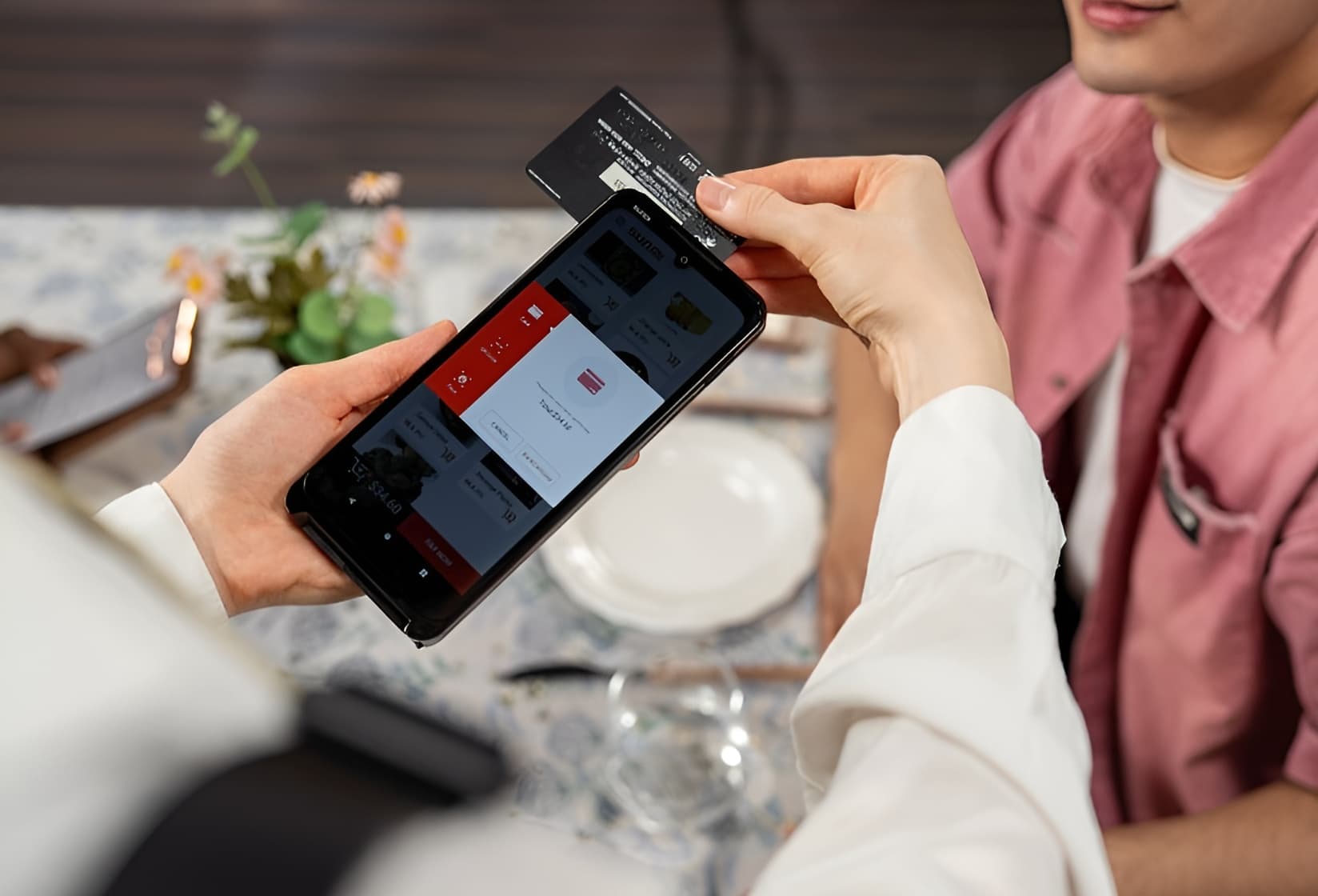 Person holding mobile payment terminal at table